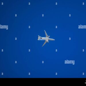 Commercial airplane flying across a clear blue sky, viewed from below.