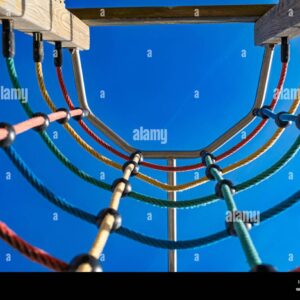Low angle view of a colorful rope climbing frame on a playground against a clear blue sky.